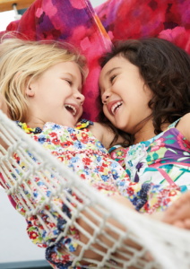 Ferien_Planung_Kurse_Muenchen_Kinder_Ferien_englisch_reiten_sport Zwei lachende Mädchen in einer Hängematter