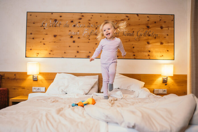 gluecksmomente_bei_den_kinderhotels Ein Kleinkind springt auf einem Doppelbett