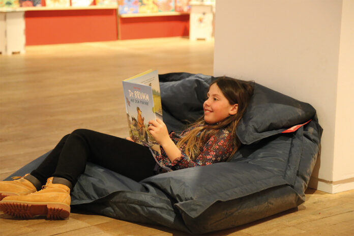 MBSJ2026_c_eickelschulte EIn Mädchen liegt in der Bücherschau auf einem Sitzsack und liest