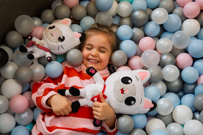 Ein Kind im Bällebad mit den Figuren aus Gabby's Dollhouse