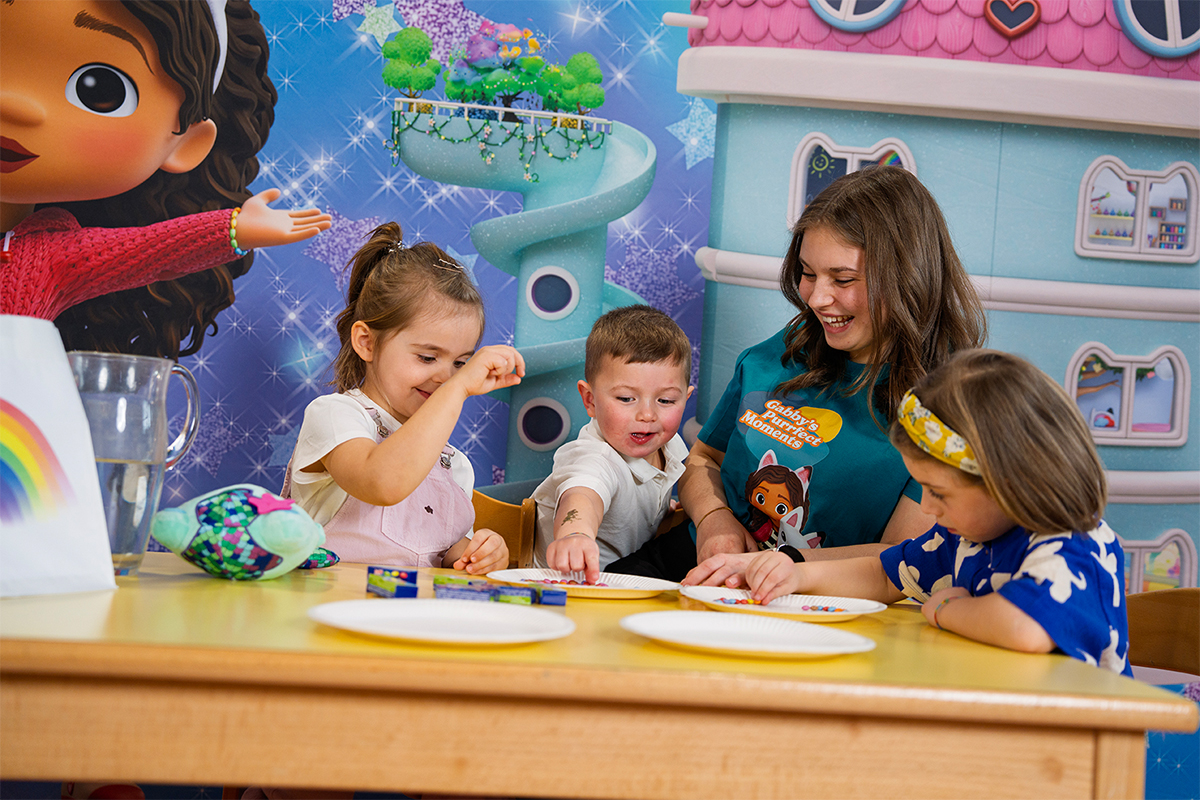 Kinder am Tisch mit Figuren aus Gabby's Dollhouse