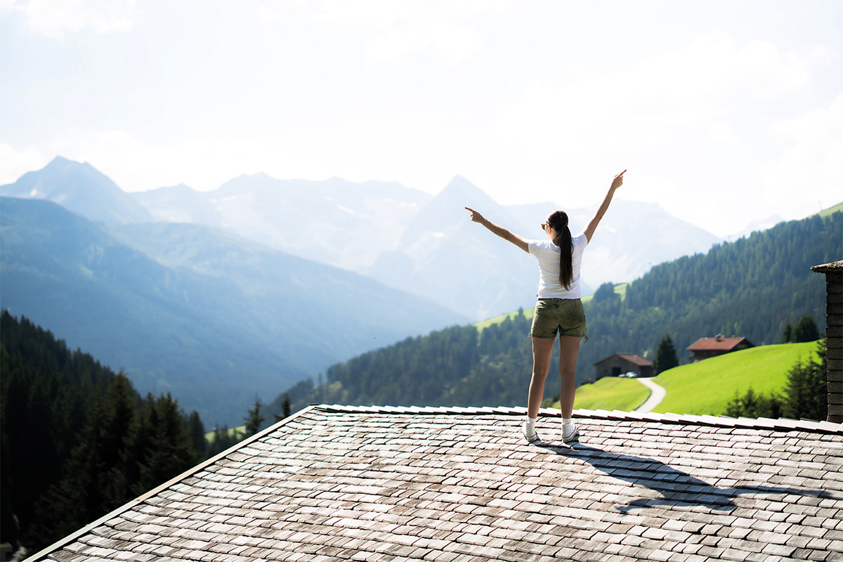 Eine Frau steht auf dem Dach einer Hütte in den Alpen