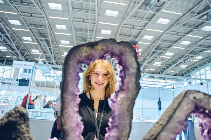 TheMunichShow Eine junge Frau steht im Bogen einer Amethystscheibe